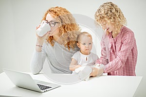 Ginger woman is drinking tea and sitting in front of the screen