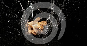 Ginger, zingiber officinale, root falling in water on black background, slow motion