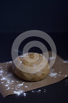 Gingerbread batter sprinkled by flour on baking paper and black background