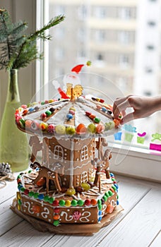 A gingerbread carousel and some Christmas decoration elements on a white wooden surface