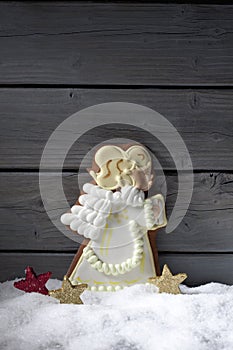 Gingerbread christmas angel star shaped decorations on heap of snow against wooden background