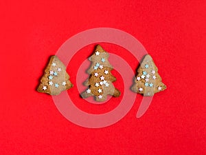 Gingerbread christmas trees cookie decorated with mastic star icing on bright red background. Festive, holiday cooking concept