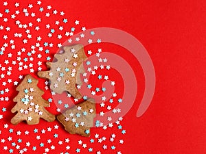 Gingerbread christmas trees cookie decorated with mastic star icing on bright red background. Festive, holiday cooking concept