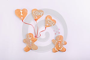 Gingerbread cookies couple for Valentines Day. Man with balloons in the shape of hearts with letteing I Love You and woman on the