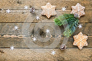 Gingerbread cookies and fir branch on wooden background with snowflakes with space for your text