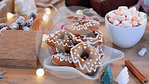 Gingerbread cookies lie on a white plate. Cookies and a cup of hot chocolate with marshmallows on a wooden table