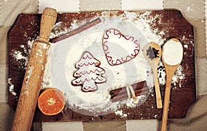 Gingerbread cookies, spices and flour over wooden cutting board