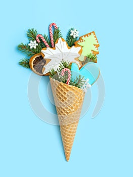 Gingerbread cookies in a waffle cone on a blue background. Spruce twigs and snowflakes