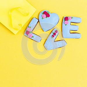 Gingerbread heart, cookies in shape of letter love with icing on pastel yellow background. Valentines day composition