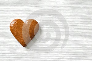 Gingerbread heart on a white background with a wood texture, can be used as a greeting card for Valentine`s Day