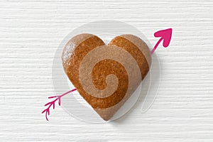 Gingerbread hearts on a white background with an arrow on white wood, can be used as a greeting card for Valentine`s Day