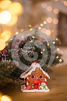 Gingerbread house. Nice souvenir. Gift. On a wooden surface against the background of blurred Christmas lights