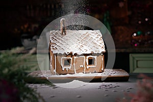 Gingerbread house sprinkled with icing sugar like snow. The spirit of Christmas. Garland on the background