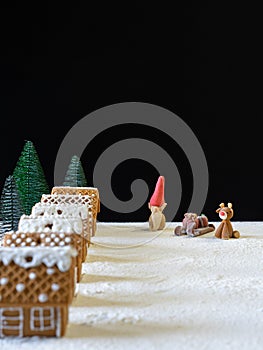 Gingerbread houses with a gnome, a moose and a sleigh with gifts. Black background for text