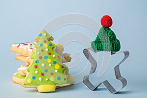 Gingerbread man cookie cutter with knitted hat and cookies isolated on blue. Winter and christmas holiday abstract