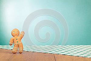 Gingerbread Man on old oak wooden table with checkered tablecloth front mint blue . Christmas card background