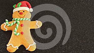 Gingerbread man with red Santa hat green and white scarf on a black background with writing space