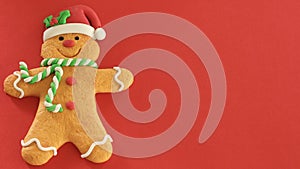 Gingerbread man with red Santa hat green and white scarf on a red background with writing space