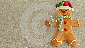 Gingerbread man with red Santa hat green and white scarf on a silver background with writing space