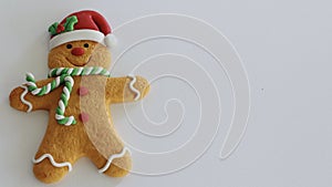 Gingerbread man with red Santa hat green and white scarf on a white background with writing space