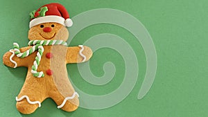 Gingerbread man with red Santa hat green and white scarf on a white background with writing space