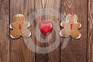 Gingerbread man and women with a heart on wooden background. Valentine`s day card.