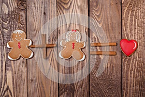 Gingerbread man and women with a heart on wooden background. Valentine`s day card.