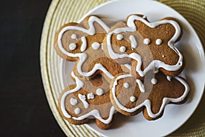 Gingerbread men on a white plate on black background