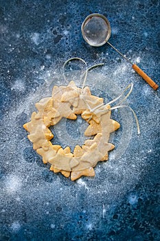Gingerbread star cookies wreath with white ribbon on a blue stone backdrop. Christmas cookies concept. Toned.