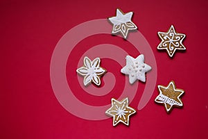 Gingerbread stars with white icing and sprinkles on red background
