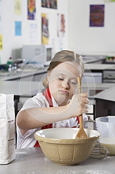 Girl (10-12) with Down syndrome mixing contents in bowl