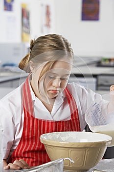 Girl (10-12) with Down syndrome pouring milk into bowl