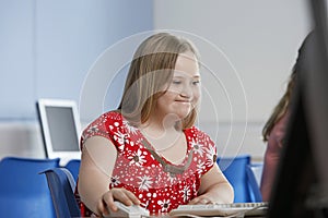 Girl (10-12) with Down syndrome using computer in computer lab