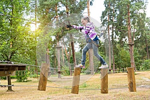 The girl is 10 years old in adventure climbing high wire park, back view, active lifestyle of children