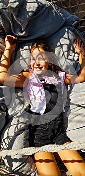 Girl 10 years old lies in hammock and smiles.