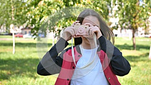 Girl 11 years old takes pictures with a toy wooden pink camera.