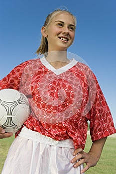 Girl (13-17) in soccer kit holding ball