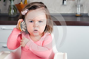 Girl 2 years old playing with a comb at home - portraying an emotional conversation on the phone.