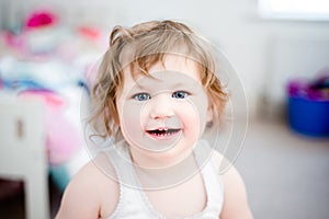 Girl (3) with bright blue eyes smiles at camera