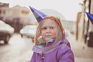 Girl (4) outdoors in winter coat and party hat