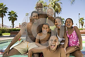 Girl (5-6) boy (7-9) boy (10-12) with parents and grandparents at swimming pool front view portrait.