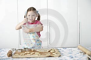 Girl (5-6) preparing cookies in kitchen