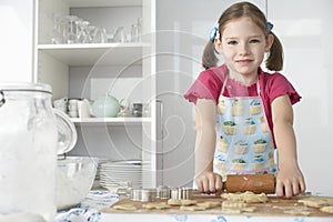 Girl (5-6) rolling dough in kitchen portrait
