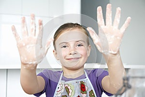 Girl (5-6) showing hands covered in flour portrait