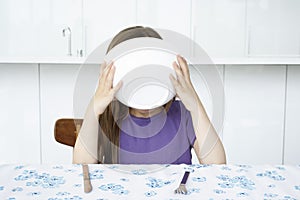 Girl (5-6) sitting at table eating cereal