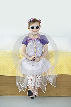 Girl (5-6) wearing costume sitting on bed portrait