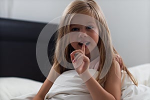 Girl 6 years old shows shaky milk tooth sitting on bed after sleep