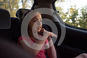 A girl of 8-10 years old rides in a car. Exploring nature, travel, family vacation. A girl of 9 years old rides in a car