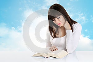 Girl absorbed in reading a book on background with sky clouds photo