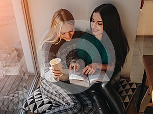 Girl absorbed in reading book during the break in cafe. Cute lovely young woman reading book and drinking coffee